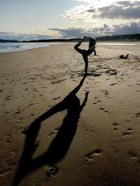 Shadow of man on sand at beach against sky