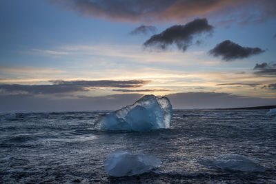 Icebergs on sea against sky during sunset