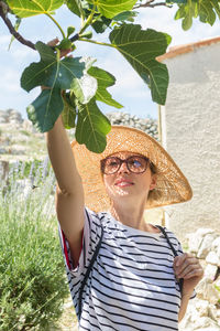 Portrait of young woman standing against plants