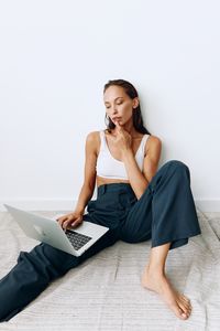 Young woman sitting on bed at home