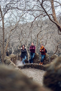 People standing by bare trees in forest