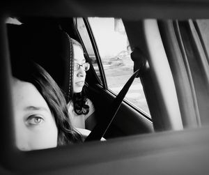 Girls sitting in car reflecting on rear view mirror