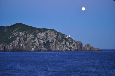 Scenic view of sea and mountains against clear blue sky