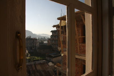 Buildings in city against sky seen through window