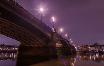 Bridge over river in city against sky at night
