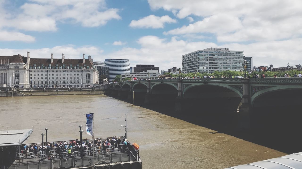 BRIDGE OVER RIVER BY BUILDINGS AGAINST SKY