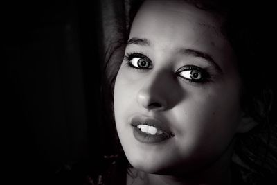 Close-up portrait of young woman against black background