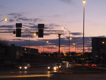 Illuminated street lights in city at sunset