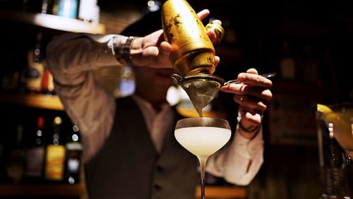 Bartender pouring liquid from shaker into cocktail glass