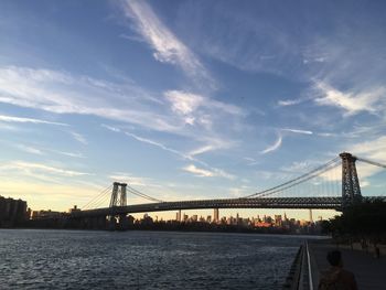 Williamsburg bridge over east river against sky during sunset