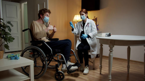 Young nurse checking temperature of patient at home