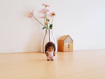 Portrait of cute girl on white table against wall at home