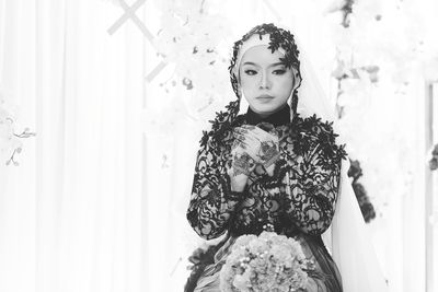 Beautiful bride wearing traditional clothing looking away while sitting in wedding ceremony