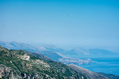 Scenic view of sea and mountains against blue sky