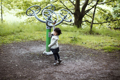 Side view of cute girl standing by outdoor play equipment in park