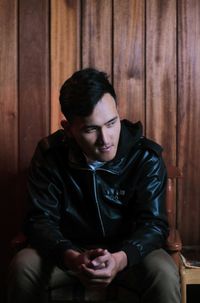 Young man looking down while sitting on chair