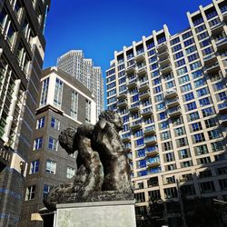 Low angle view of statue against buildings in city against sky