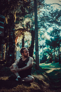 Thoughtful man sitting on land in forest