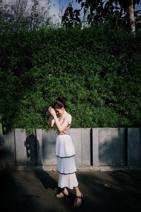 Woman standing by tree against plants