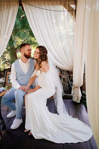 Newlywed bridegroom embracing while sitting outdoors