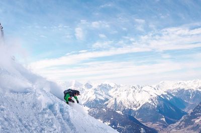 Man skiing on snowcapped mountain against sky