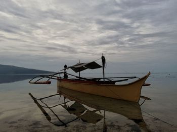 Fishing boat moored on beach against sky