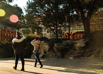 Rear view of people walking on sidewalk in city