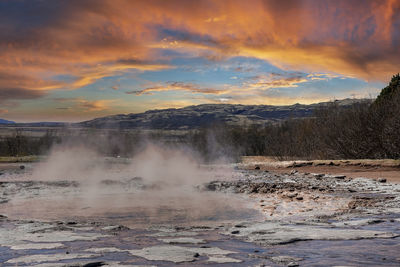 Smoke emitting from geothermal field at smidur geyser valley against cloudy sky