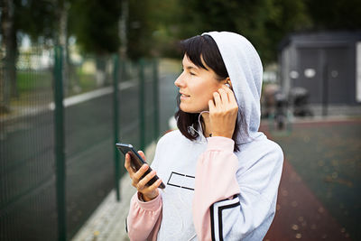A caucasian woman uses a smartphone via wired headphones with a headset. phone in hand