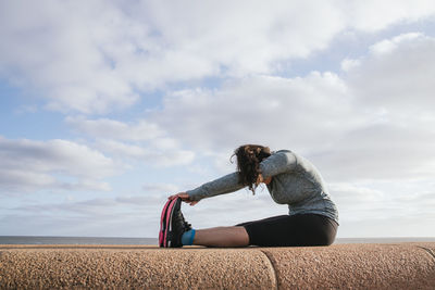 Woman sitting down stretching her legs.