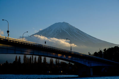 Bridge over river by snowcapped mountain against sky