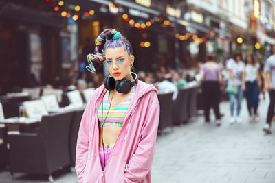 Portrait of cool hipster young girl with trendy eyeglasses and street style clothes in city street