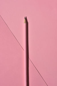 High angle view of sharp wooden pencil on pink background.