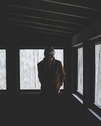 Young man looking through window at home