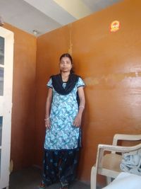 Portrait of young woman standing against wall