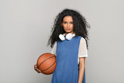 Portrait of a teenage girl holding ball against white background