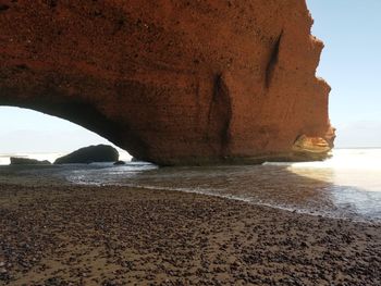 Rock formation on beach against sky