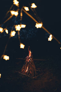 Close-up of illuminated string lights against bonfire on land at night