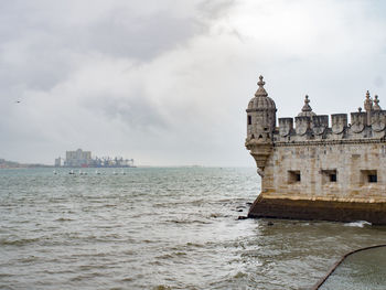 View of building by sea against cloudy sky