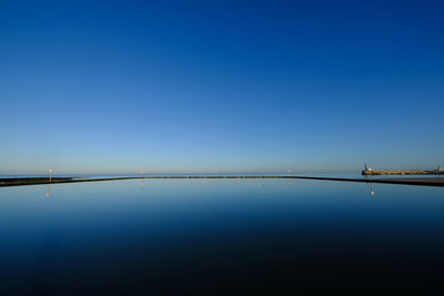 Scenic view of lake against clear blue sky