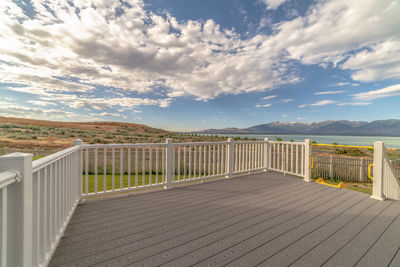 Wooden railing on footpath against sky