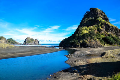 Scenic view of sea and mountains against blue sky