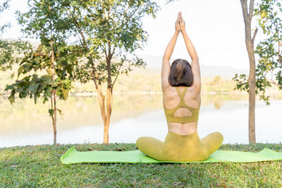 Young attractive and active woman stretching on a green yoga mat while practicing her morning yoga