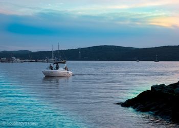 People on sailboat in sea against sky