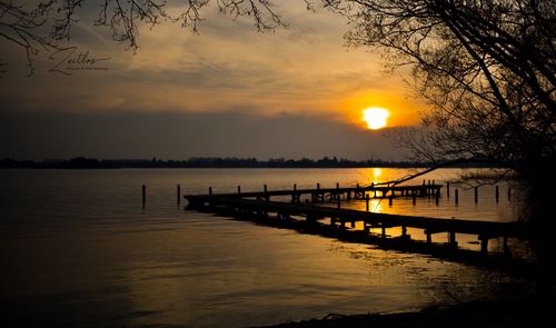 Silhouette pier over lake against sky during sunset