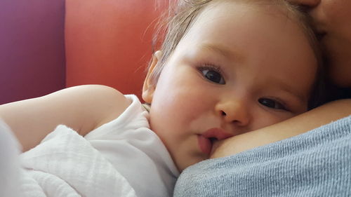 Cropped image of mother breastfeeding baby on bed