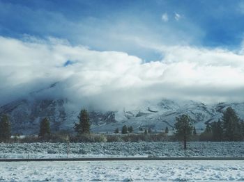 Snow covered landscape against cloudy sky