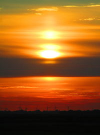 Scenic view of silhouette field against orange sky