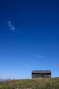 Built structure on field against clear blue sky