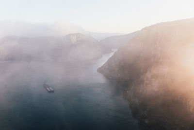 Majestic foggy autumn landscape with cargo ship on water at sunrise . danube river, gorge